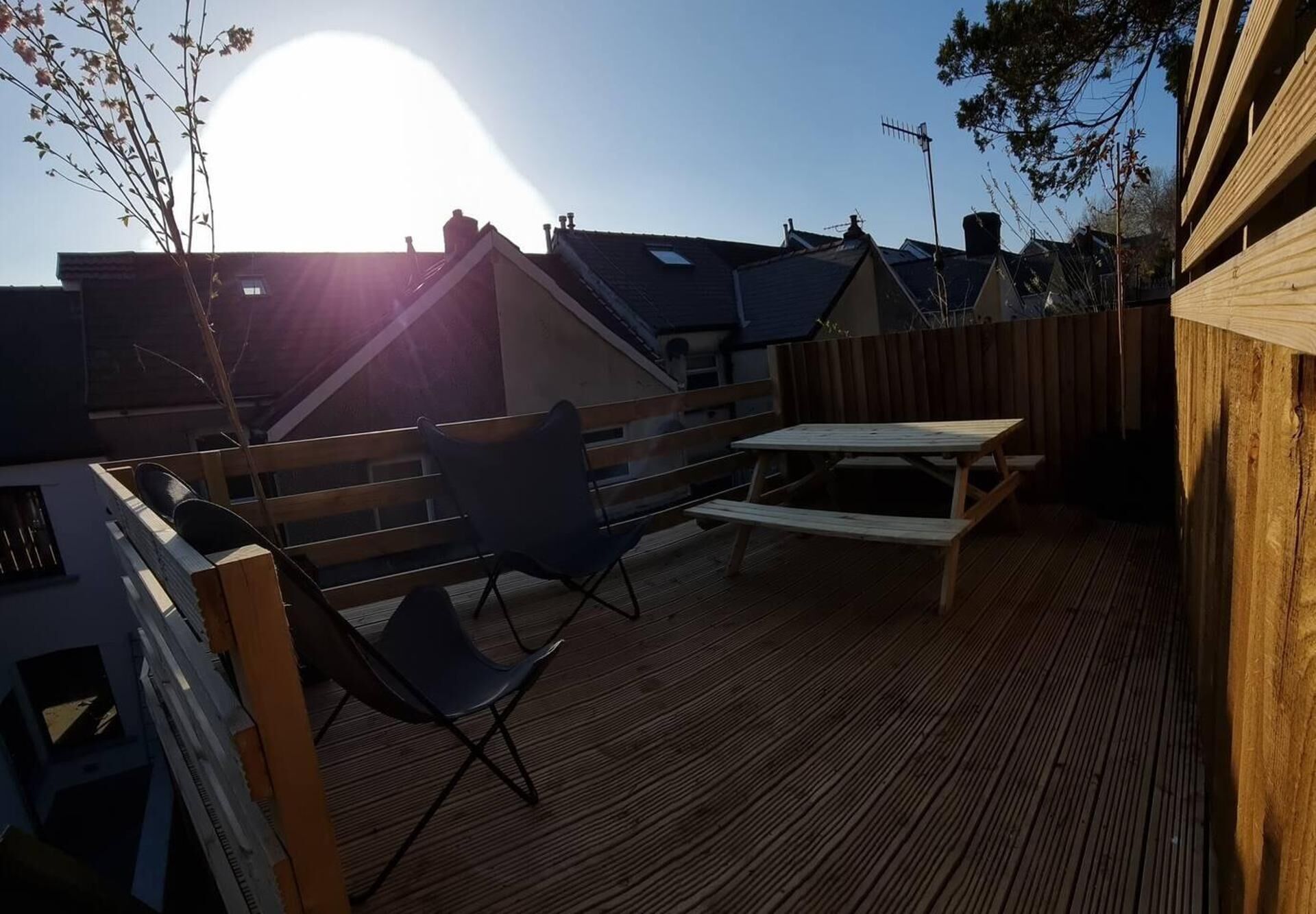 A wooden deck with a picnic table and chairs, surrounded by a wooden fence.