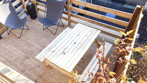 A wooden deck with a table and two chairs.
