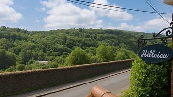 A sign reading "Hillview" with a view of a lush green landscape and a stone wall.