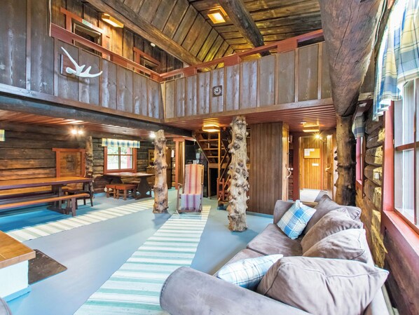 Un intérieur rustique avec un plafond en bois, un canapé agrémenté de coussins à carreaux et un tapis rayé.
