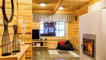 A cozy cabin interior with a fireplace, wooden walls, a television, and a window with a view.