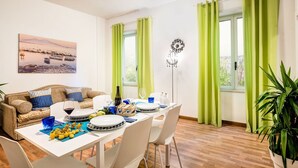 A dining area with a table set for a meal, a sofa, and a painting on the wall. - Nice apartment for 4 guests with WIFI, A/C and TV (Sorrento)