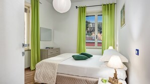 A bedroom with a bed, a bedside table with a lamp, a mirror, and a window with curtains. - Nice apartment for 4 guests with WIFI, A/C and TV (Sorrento)