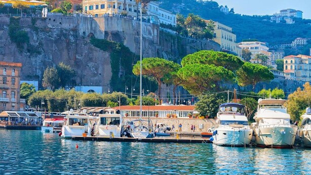 A marina with boats docked, a waterfront promenade, and buildings on a hillside. - Beautiful apartment for 4 guests with A/C, WIFI and TV (Sorrento)