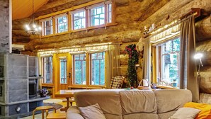 Un interior acogedor de cabaña de madera con un sofá, una mesa de comedor y una chimenea.
