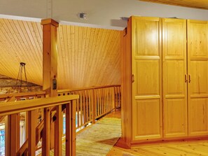A wooden interior with a high ceiling, a wooden staircase, and a large wardrobe.