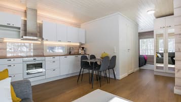 Ett modernt kök med vita skåp, ett matbord med stolar och en inbyggd ugn.