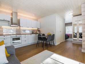 Een moderne keuken met witte kasten, een eettafel met stoelen en een ingebouwde oven.
