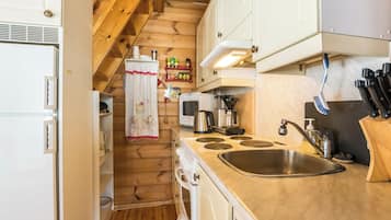 Cocina compacta con paredes de madera, estufa integrada, pileta y microondas.