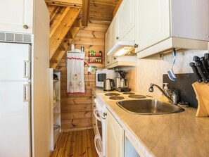 Een compacte keuken met houten wanden, een ingebouwde kookplaat, een spoelbak en een magnetron.