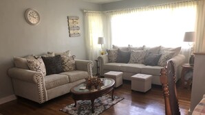 Un salon avec deux canapés, une table basse et une horloge au mur.