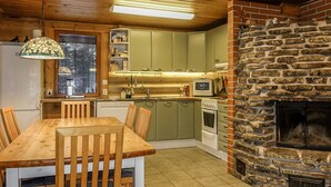 A cozy kitchen with wooden cabinets, a stone fireplace, and a dining area with a wooden table and chairs.