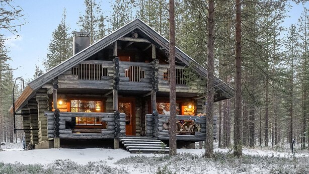 A log cabin with a central entrance, multiple windows, and a porch area.