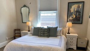 A neatly made bed with a white comforter and pillows, a nightstand with a lamp, a chair, and a framed picture on the wall. - Luxury Retreat in Prime Downtown Spring Green Location  (Spring Green)