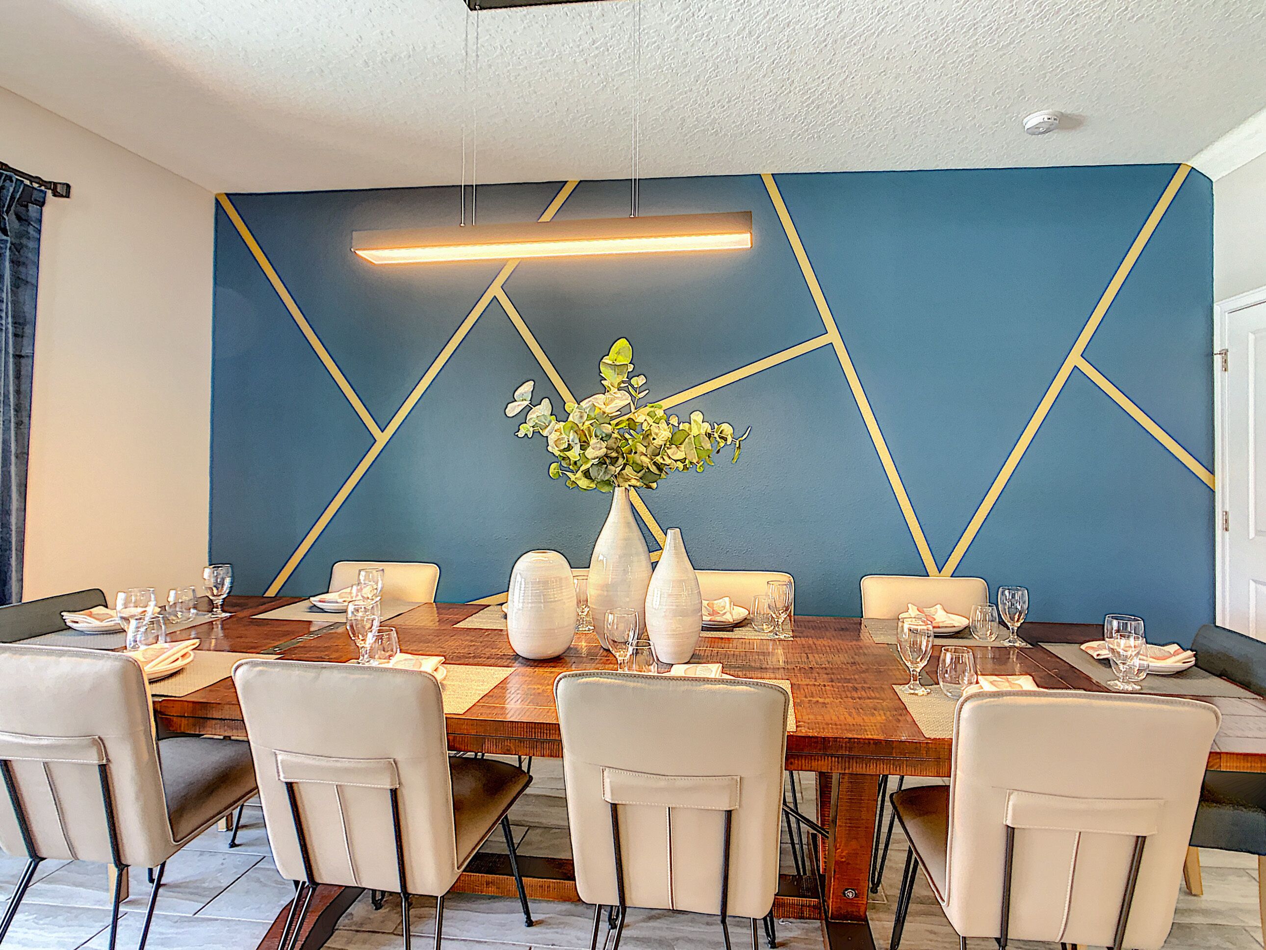 Un espace repas avec une longue table en bois, dressée pour six personnes, entourée de six chaises.