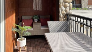 A covered outdoor seating area with wicker furniture, a macrame wall hanging, and a potted plant.