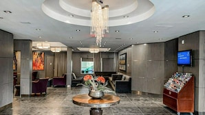 A lobby with a round table, seating area, and a television screen.