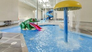 An indoor water park with a large frog slide, a water fountain, and a blue slide in the background.
