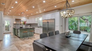 Una cucina moderna con isola centrale, elettrodomestici in acciaio inossidabile e un'area pranzo con un tavolo grande e sedie.