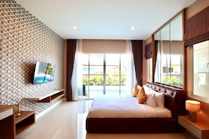 Een moderne hotelkamer met een groot bed, een flatscreen televisie bevestigd aan een gestructureerde muur, een glazen schuifdeur naar een zwembad en een groot raam met gordijnen.