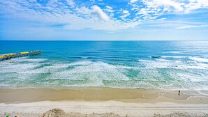 A beach with a pier extending into the ocean, clear skies, and calm waves. - Oceanfront-Pool-Aruba #905-EV Charging (Daytona Beach Shores)