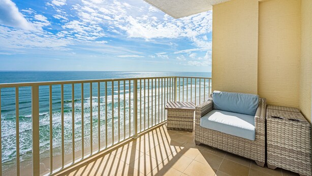 A balcony with a wicker sofa and table, overlooking the ocean. - Oceanfront-Pool-Aruba #905-EV Charging (Daytona Beach Shores)