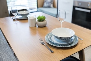 Enjoy a romantic dinner for two in this elegantly set dining area, complete with a potted plant and a glimpse of the adjacent kitchen.