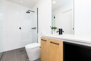 Bathroom features a glass shower enclosure, white toilet, and wooden cabinet.