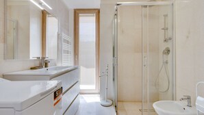 A modern bathroom with a glass-enclosed shower, a sink, and a mirror.