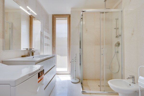 A modern bathroom with a glass-enclosed shower, a sink, and a mirror. - 5-Star Barcola Apartment - 50 meters from the sea (Trieste)