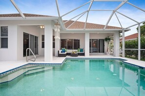 Relax by the rectangular pool surrounded by a tiled deck and shaded patio area with a seating space.