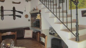 A dining area with a wooden table and chairs, a fireplace, and a staircase with a decorative railing.