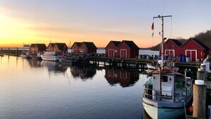 A harbor with red buildings, calm water, and boats docked.