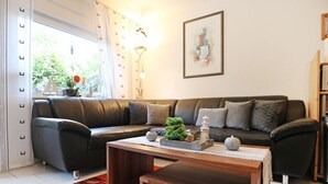 A modern living room with a dark leather sofa, a wooden coffee table, and a red patterned rug.