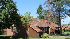 A row of cabins with sloped roofs, surrounded by trees and grass.