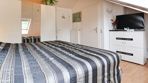 A bedroom with a bed, a TV, a wardrobe, and a plant.