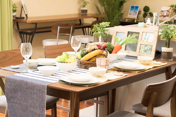 Guests can enjoy meals at a beautifully set table with fresh fruits and vegetables, surrounded by comfortable chairs.