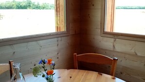 Una mesa de madera para comer con un florero, una botella y cubiertos.