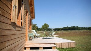 Una cabaña de madera con terraza y mobiliario exterior.