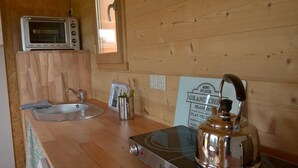 Cocina compacta con encimera de madera, horno tostador, hervidor, pileta y un cartel con opciones de menú.