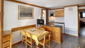 Una cocina compacta con armarios de madera, una mesa de comedor y un microondas.