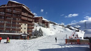 Un edificio de madera de varios pisos con balcones, probablemente un hotel, frente a un paisaje montañoso nevado.