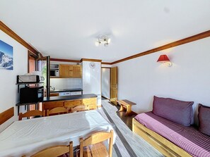 A compact room with a kitchenette, a dining area, and a bed.