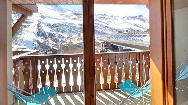Un balcón con vistas a montañas nevadas y un edificio moderno.