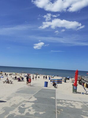 Une plage avec des gens, des tables de pique-nique et une promenade en bois.