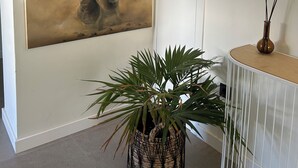 Une pièce décorée d’un grand tableau représentant un éléphant, d’une plante en pot et d’une console blanche ornée d’un vase et de bougies.