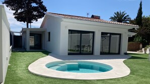 Une maison moderne dotée d’une piscine, d’une terrasse et d’une pelouse bien entretenue.