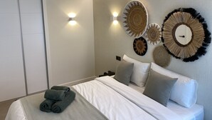 Une chambre d’hôtel moderne avec un lit soigneusement fait, des objets décoratifs accrochés au mur et une armoire bien visible.