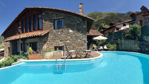 Un edificio de piedra con piscina, mobiliario exterior y vistas del paisaje circundante.