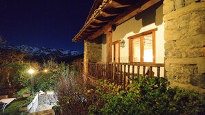 Edificio de piedra con balcón de madera y montañas al fondo.